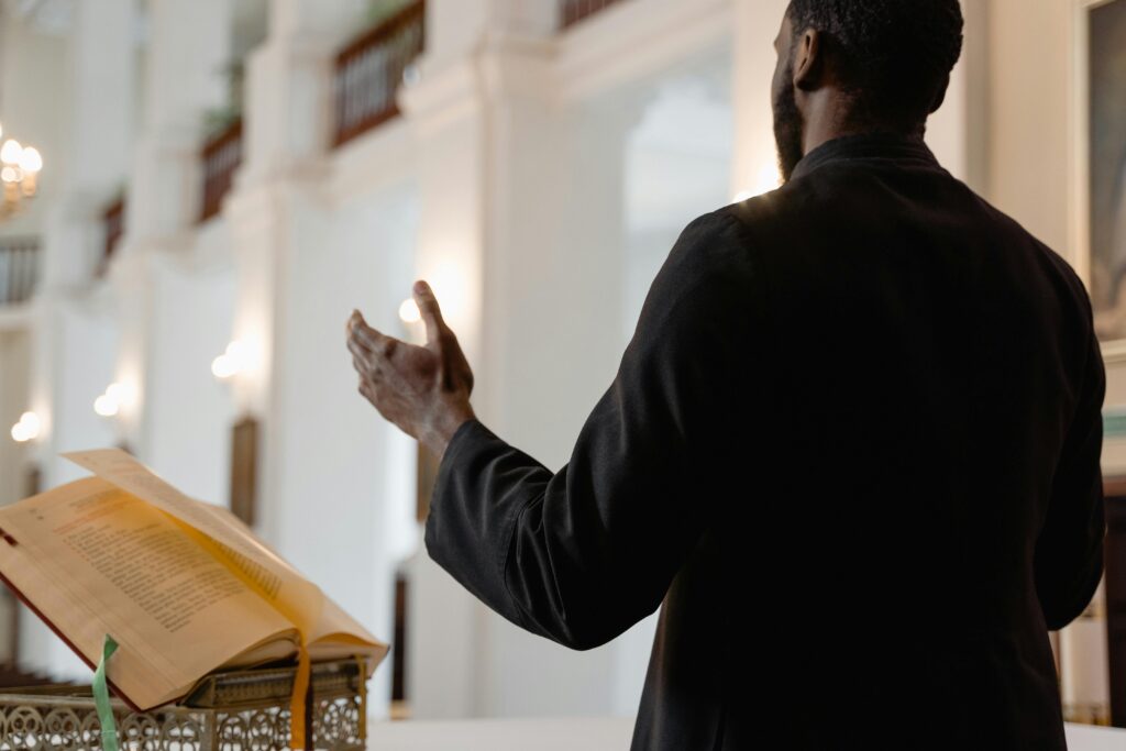A priest delivers a sermon inside a beautifully lit church, standing at an altar.