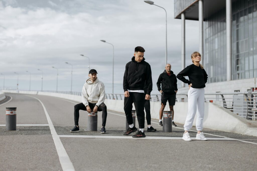 Four adults posing stylishly in sportswear in an urban street setting.